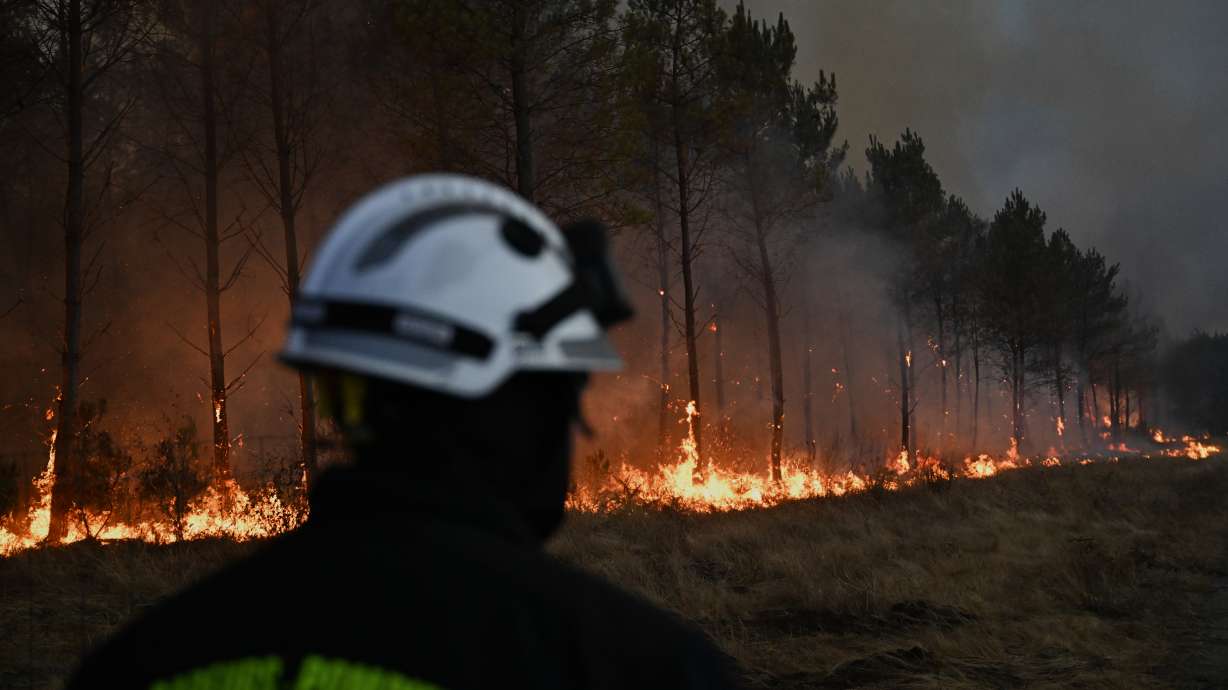 A firefighter walks in front of burning trees as a wildfire rages near Marcheprime, outside, Bordeaux, France, Sunday.