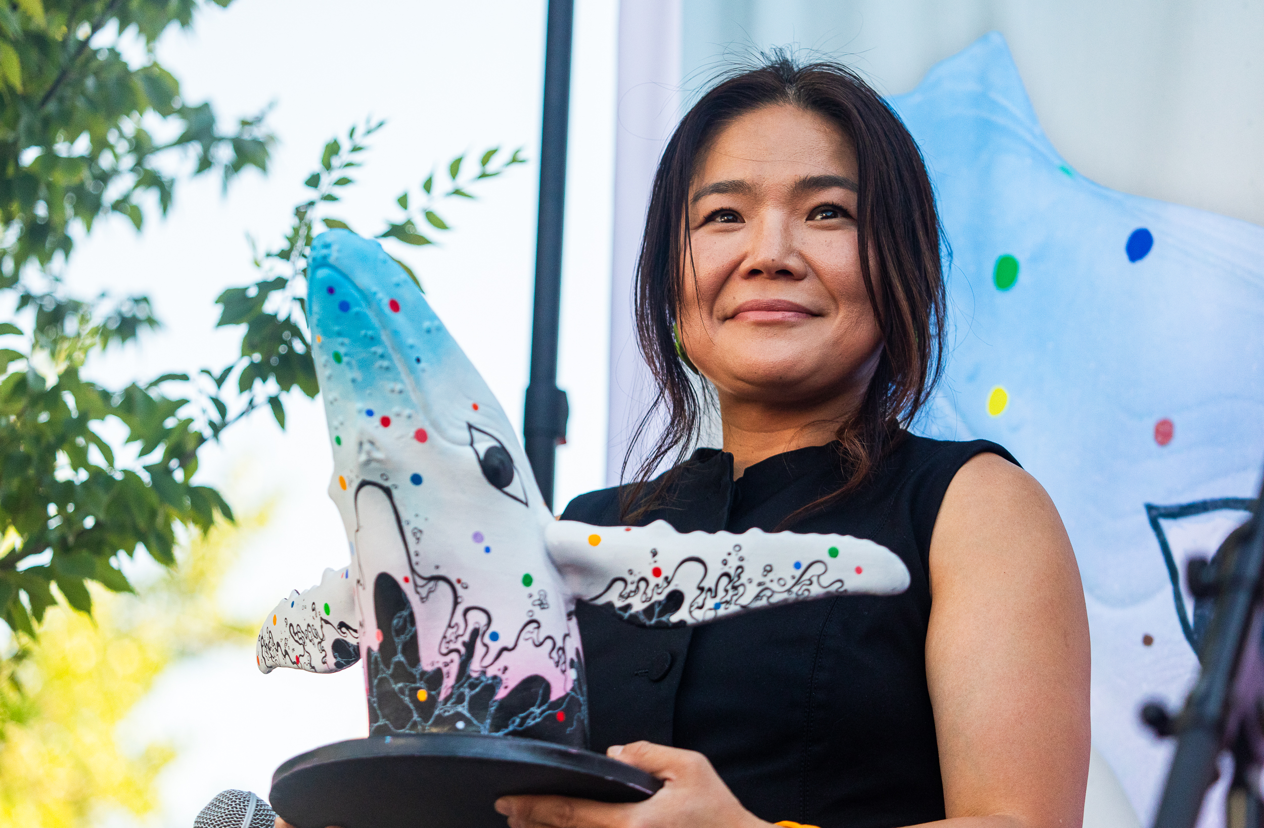 Salt Lake-based artist Jiyoun Lee-Lodge holds up a model of her mural "Open Your Eyes" during an unveiling of the new mural for "Out of the Blue" in Salt Lake City on Saturday. The mural will be painted on the city's whale sculpture in the coming weeks. 