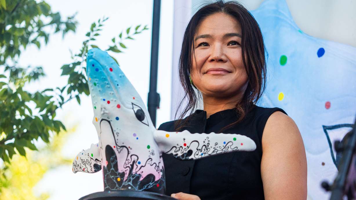 Salt Lake-based artist Jiyoun Lee-Lodge holds up a model of her mural "Open Your Eyes" during an unveiling of the new mural for "Out of the Blue" in Salt Lake City on Saturday. The mural will be painted on the city's whale sculpture in the coming weeks.