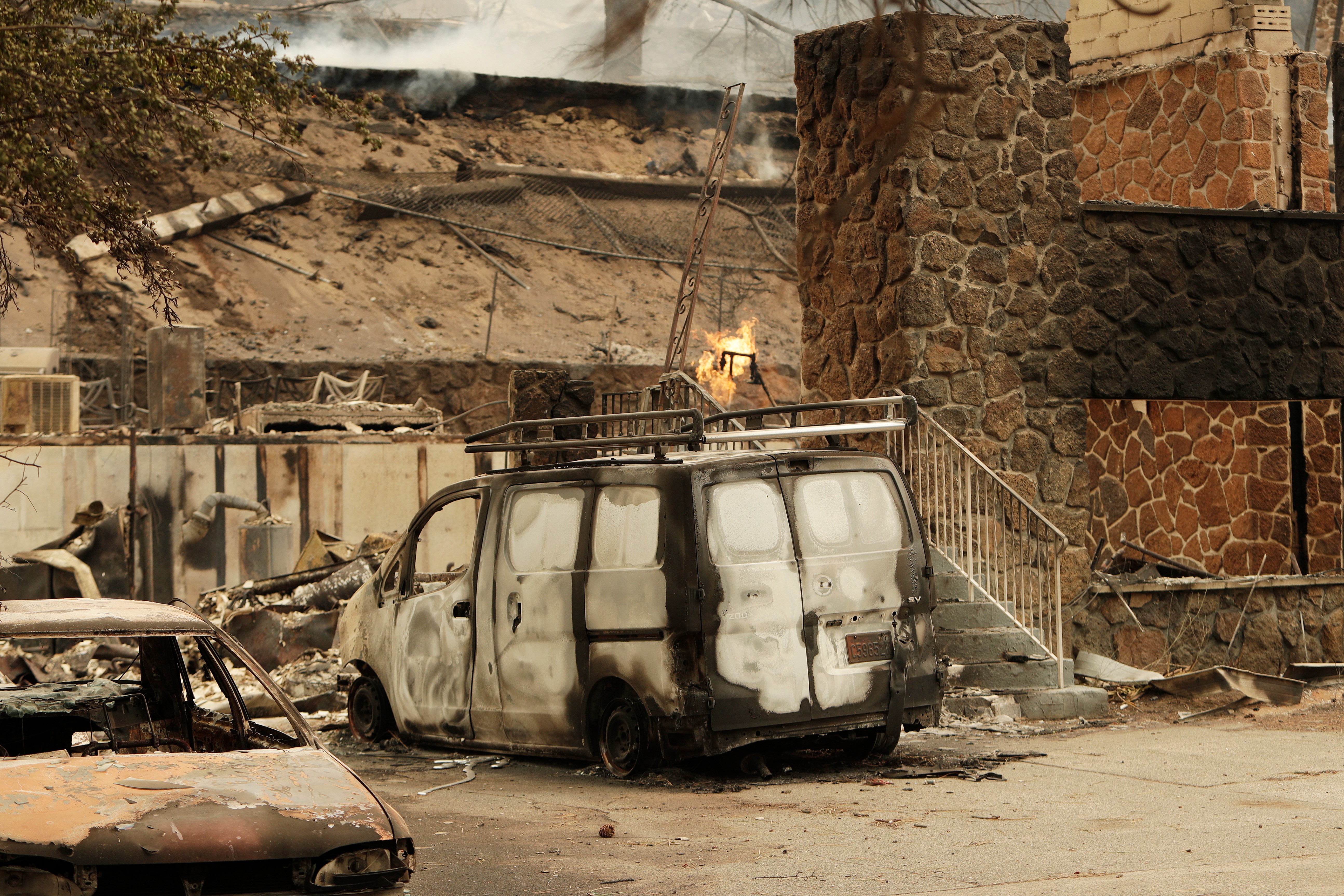 A charred van is parked by a building that burned down on W. Indian Trail Rd. in the aftermath of a wildfire in Spokane, Wash., on Sunday.