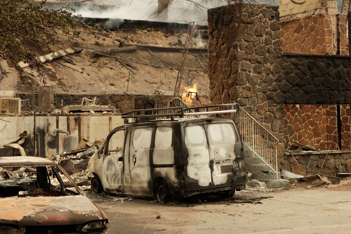 A charred van is parked by a building that burned down on W. Indian Trail Rd. in the aftermath of a wildfire in Spokane, Wash., on Sunday.