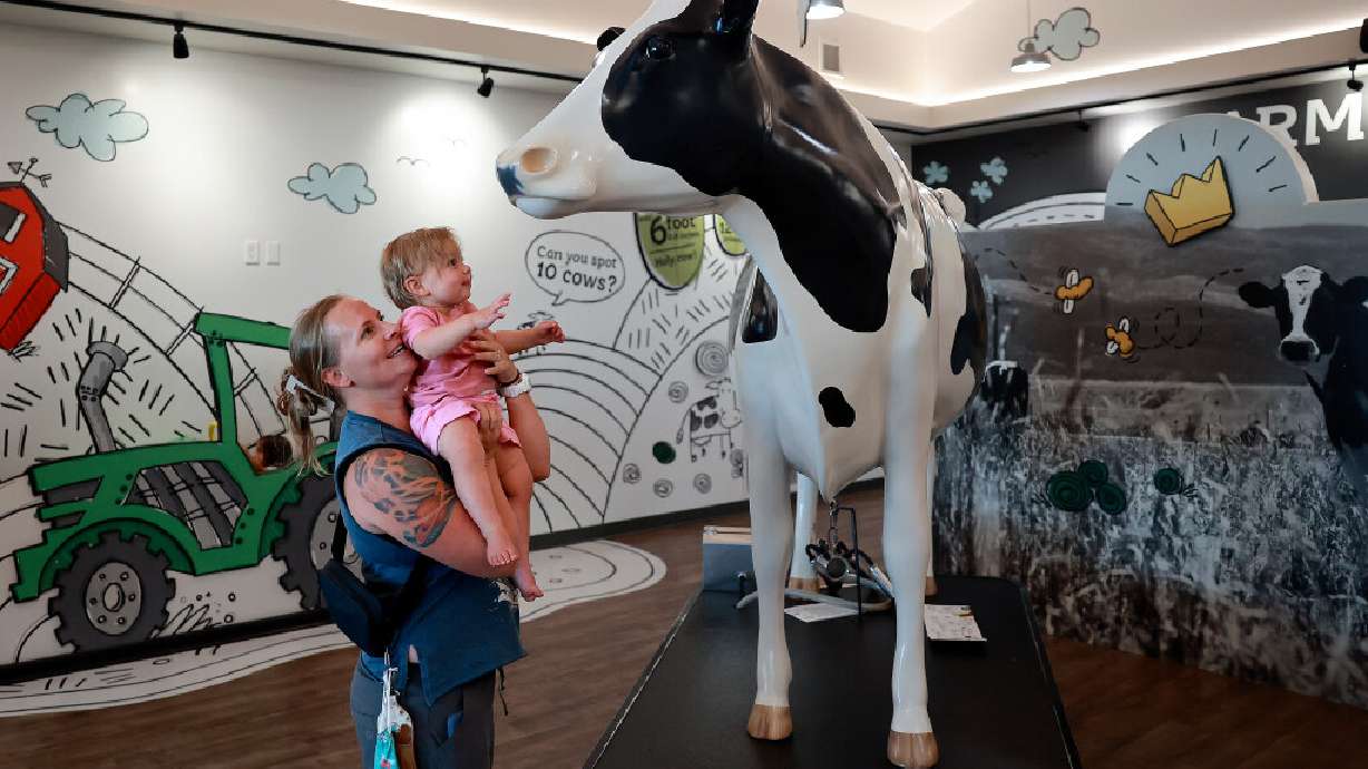 Kira Freeman holds her daughter Luna Freeman up to look at a cow statue at The Creamery in Beaver on Thursday, July 9, 2026.