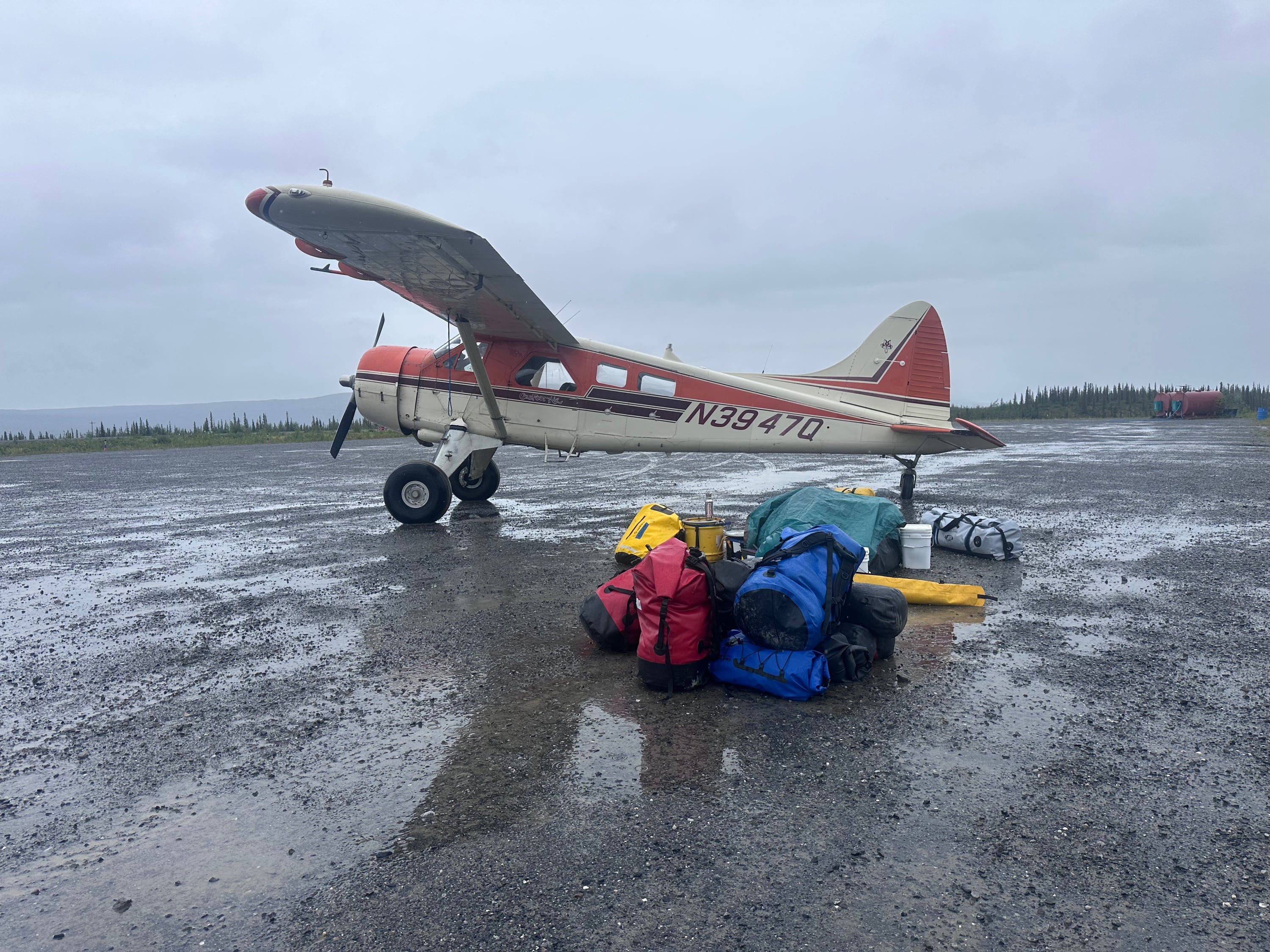 Dirk Nickich, the proprietor of Coyote Air, arrives in his de Havilland Beaver bush plane, nicknamed “Pumpkin” on June 29. Gear going with the first group to be ferried into the Arctic National Wildlife Refuge’s backcountry is laid out by weight and need.