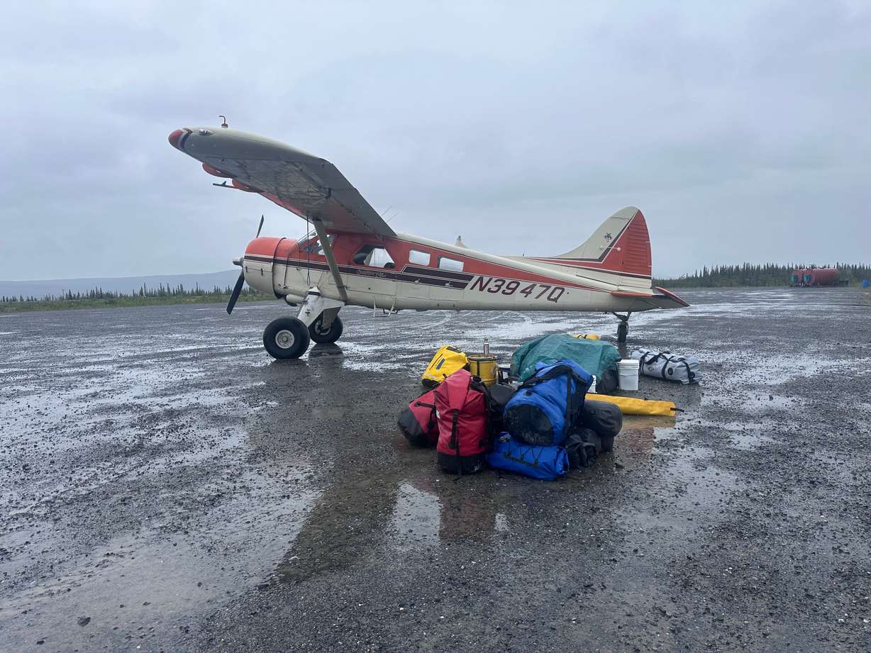 Dirk Nickich, the proprietor of Coyote Air, arrives in his de Havilland Beaver bush plane, nicknamed “Pumpkin” on June 29. Gear going with the first group to be ferried into the Arctic National Wildlife Refuge’s backcountry is laid out by weight and need.