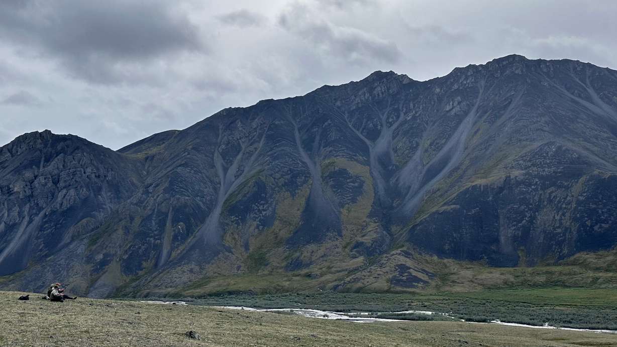 A group of visitors take in the valley views while sitting on the tundra after several days of rain in the Arctic National Wildlife Refuge in Alaska on the evening of June 29.