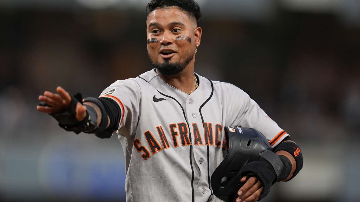 San Francisco Giants' Luis Arraez jokes with players in the San Diego Padres dugout as he stands on first base after getting hit by a pitch during the fourth inning of a baseball game Thursday, July 30, 2026, in San Diego.