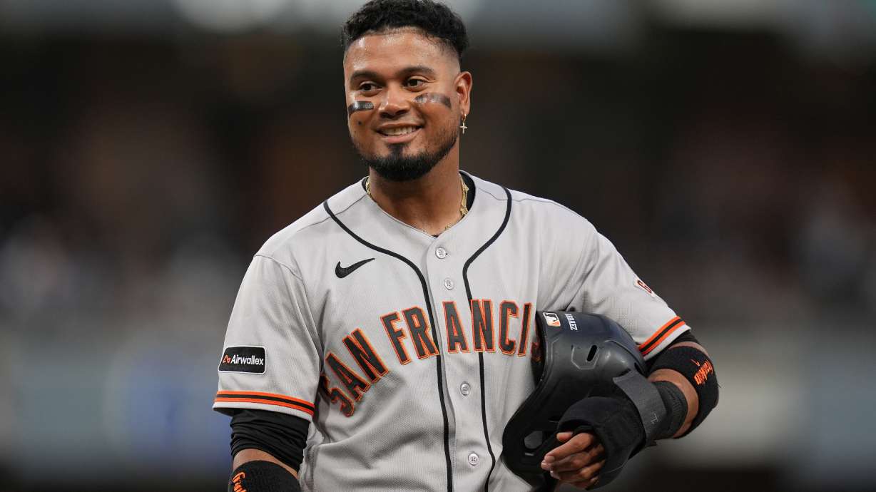 San Francisco Giants' Luis Arraez jokes with players in the San Diego Padres dugout as he stands on first base after getting hit by a pitch during the fourth inning of a baseball game Thursday, July 30, 2026, in San Diego.
