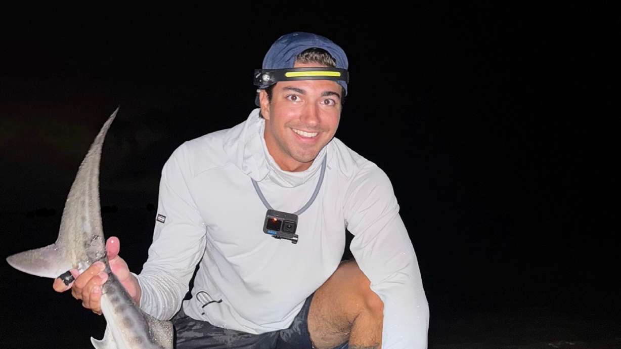 This photo provided by Nelson Rouette shows his brother, Nate Rouette, holding a young tiger shark that they caught off Falmouth Mass., July 23.