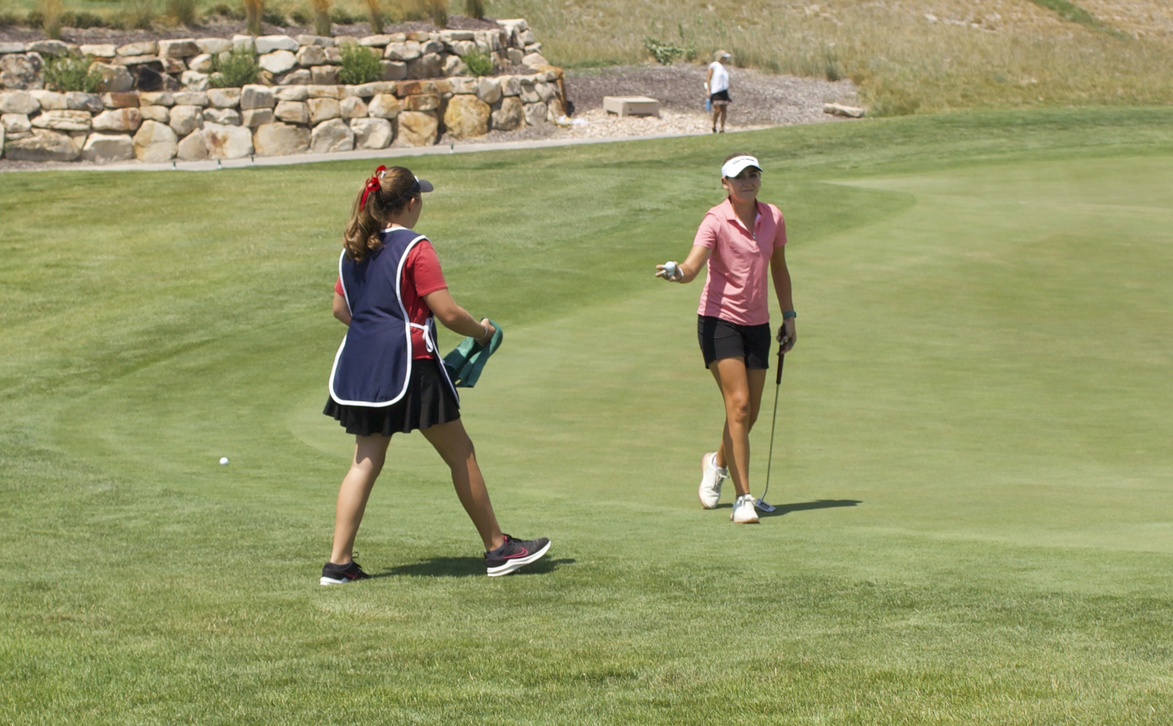 Pro golfer Ali Mulhall hands a ball to her sister during the opening round of the Larry H. Miller Utah Women's Open, Monday, Aug. 3, 2026 at TalonsCove Golf Course in Saratoga Springs, Utah.