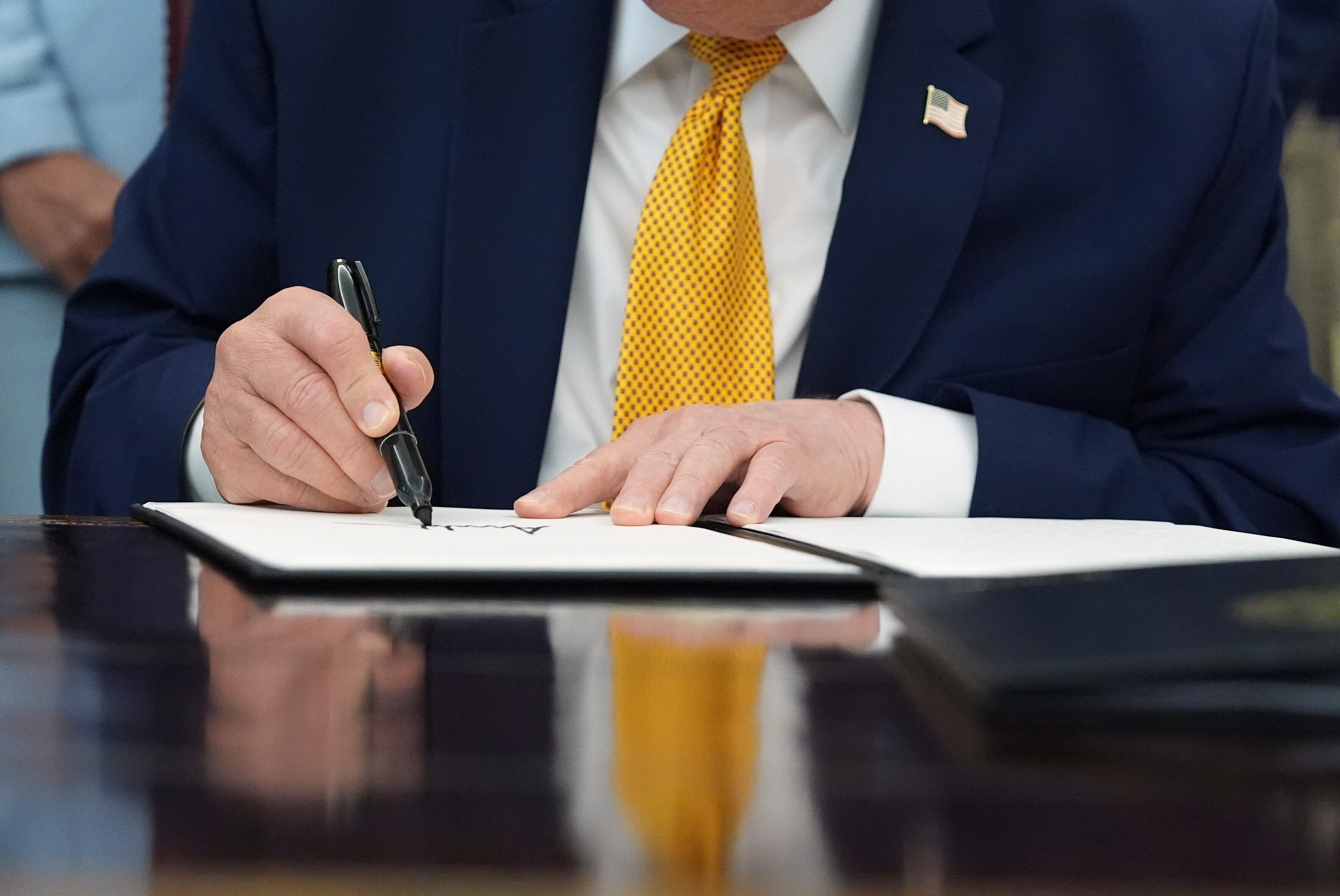 President Donald Trump signs the Military Spouse Commission executive order during a meeting about military families, in the Oval Office of the White House, Monday in Washington.