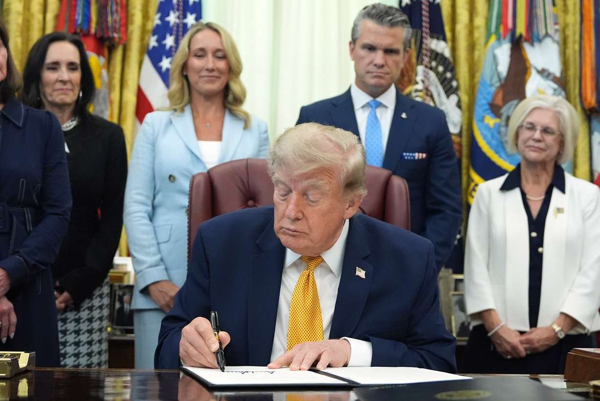President Donald Trump signs the Military Spouse Commission executive order as Jennifer Hegseth, center left, Defense Secretary Pete Hegseth, center right, and guests watch during a meeting about military families, in the Oval Office of the White House, Monday in Washington.