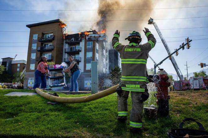 A member of the Sandy City Fire Department motions after connecting a hose to a fire hydrant as fellow firefighters respond to an apartment fire at 942 E. North Union Ave. near Hillcrest High School in Midvale on Friday.