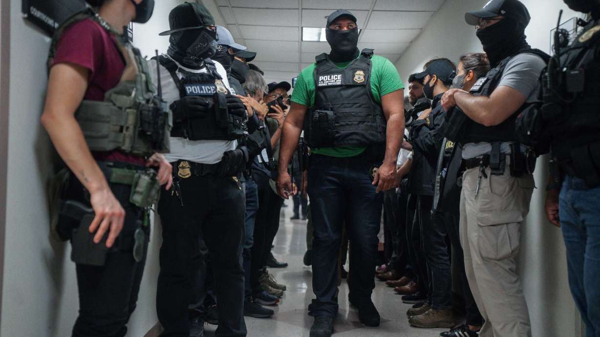 Masked federal agents wait outside an immigration courtroom, July 8, 2025, in New York. New York can't ban federal agents from wearing face coverings or require that they wear visible identification, a federal judge ruled Monday.