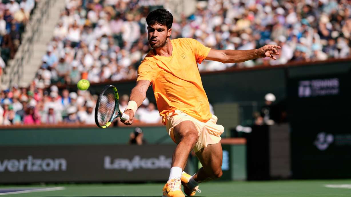 FILE - Carlos Alcaraz, of Spain, returns a shot against Daniil Medvedev, of Russia, during a semifinal match at the BNP Paribas Open tennis tournament, March 14, 2026, in Indian Wells, Calif.