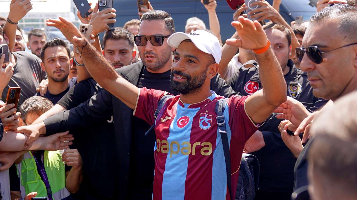Egypt's Mohamed Salah wearing his new Trabzonspor team jersey gestures to supporters as he arrives at the airport in Istanbul, Turkey, Wednesday, Aug. 5, 2026.