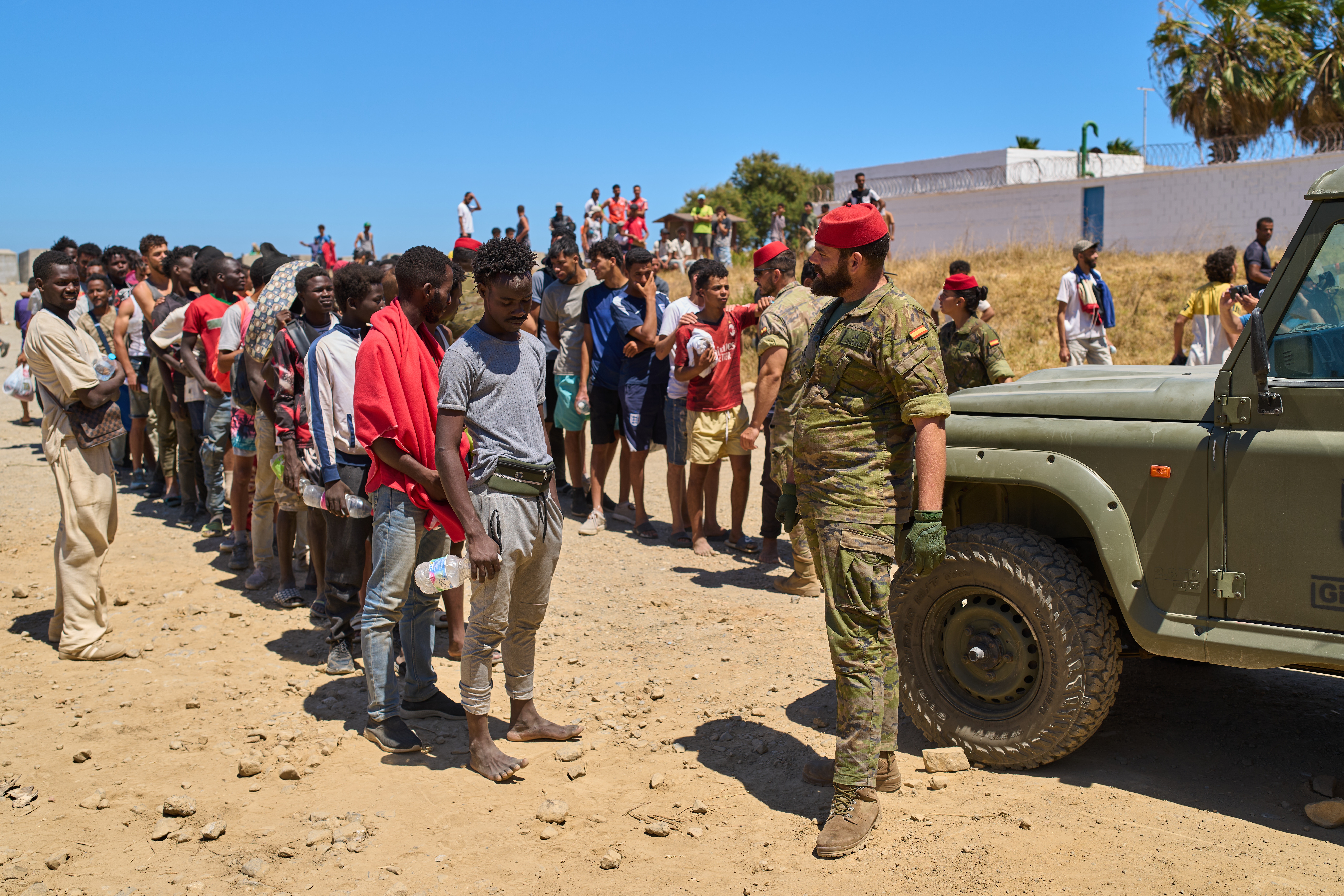 Migrants who crossed into Spain from Morocco line up for water distributed by Spanish soldiers in the Spanish enclave of Ceuta, Sunday, Aug. 2, 2026. 