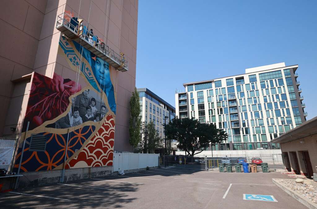 Cole Eisenhour paints a mural overlooking the parking lot behind the Salt Lake Buddhist Temple in Salt Lake City on Aug. 4. The parking lot is used as a beer garden during festivals and for services.