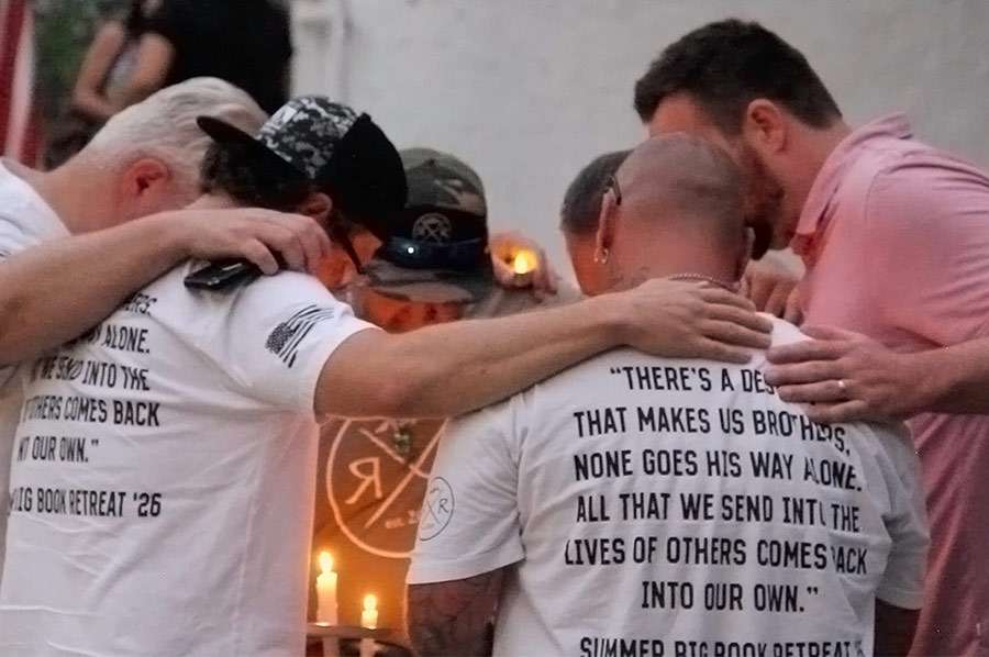 A group of men pray at the candlelight vigil for the victims of the In-N-Out shooting at the Twin Falls City Park in Idaho, Tuesday. Three people were killed, including the gunman, and seven more were injured in the shooting.