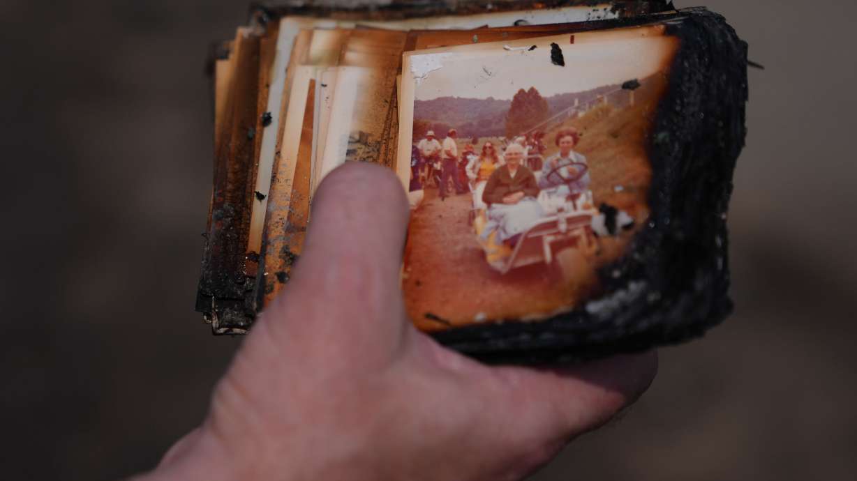 Mike Wirth holds family photos retrieved from his father-in-law's home after a wildfire hit the northwest part of Spokane, Wash., on Tuesday. Fire weather is scheduled to return to the area this weekend as crews continue to battle already burning blazes.
