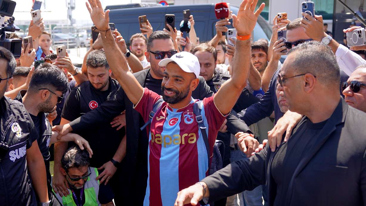 Egypt's Mohamed Salah wearing his new Trabzonspor team jersey gestures to supporters as he arrives at the airport in Istanbul, Turkey, Wednesday, Aug. 5, 2026.