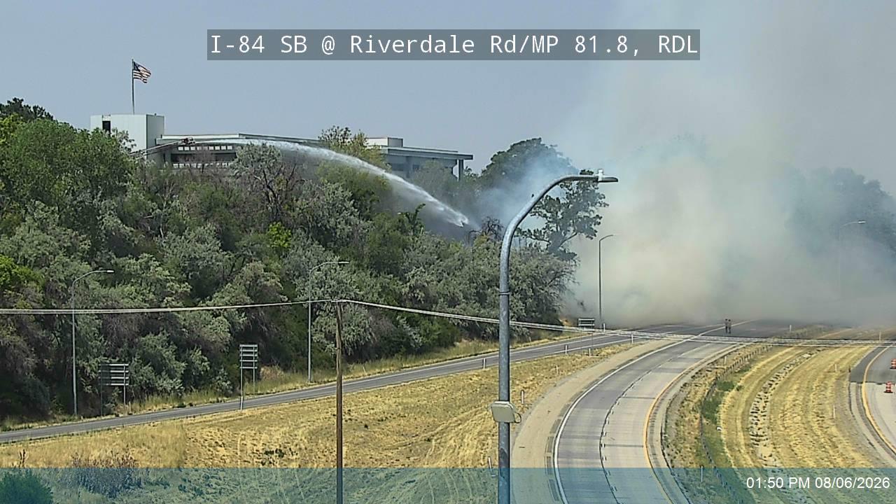 Firefighters pour water on a fire that threatened a building along Interstate 84 on Thursday.