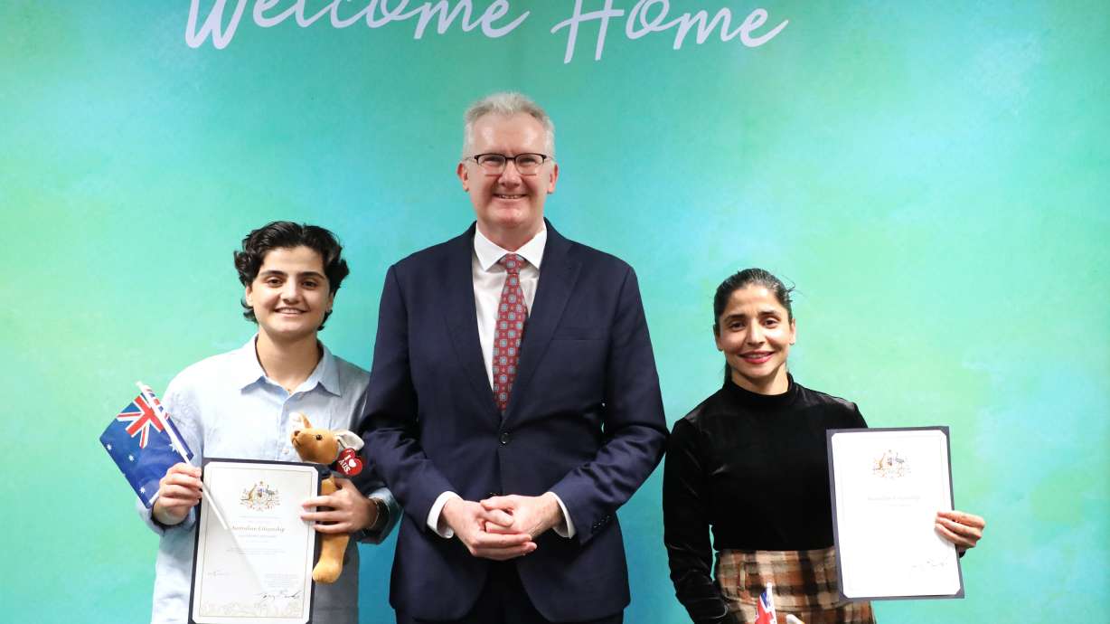 Fatemeh Pasandideh, left, and Atefeh Ramezanisadeh, former members of the Iranian women’s soccer team, stand with Australia's Minister for Home Affairs, Tony Burke, after receiving their citizenship in Brisbane, Australia, Wednesday, Aug. 5, 2026.