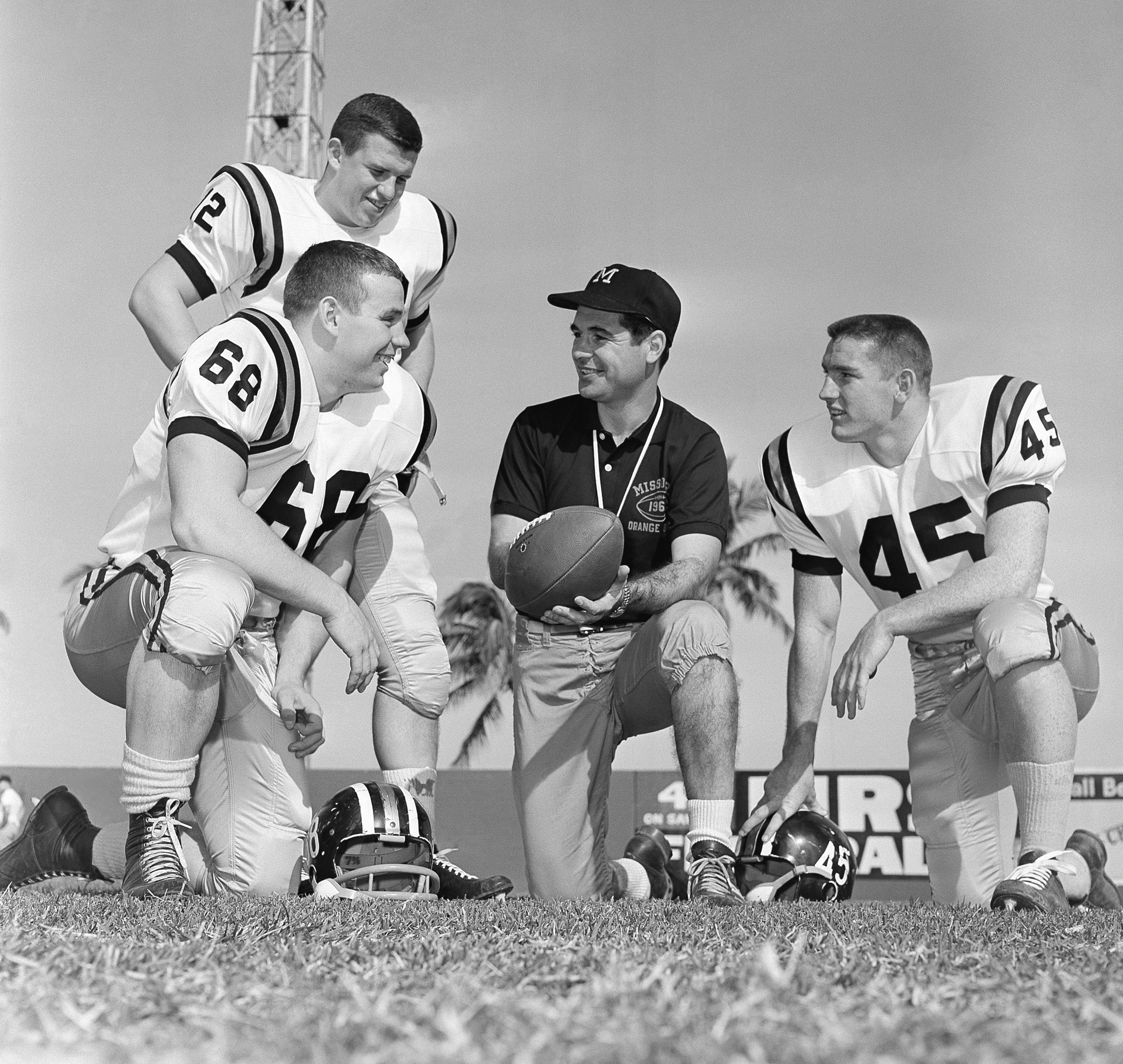 FILE - Missouri head coach Dan Devine, center, meets with three of his girders, Paul Henley (68), guard; Ron Tayler (12), quarterback; and Donnie Smith (45), halfback, in Miami on Dec. 27, 1960. 