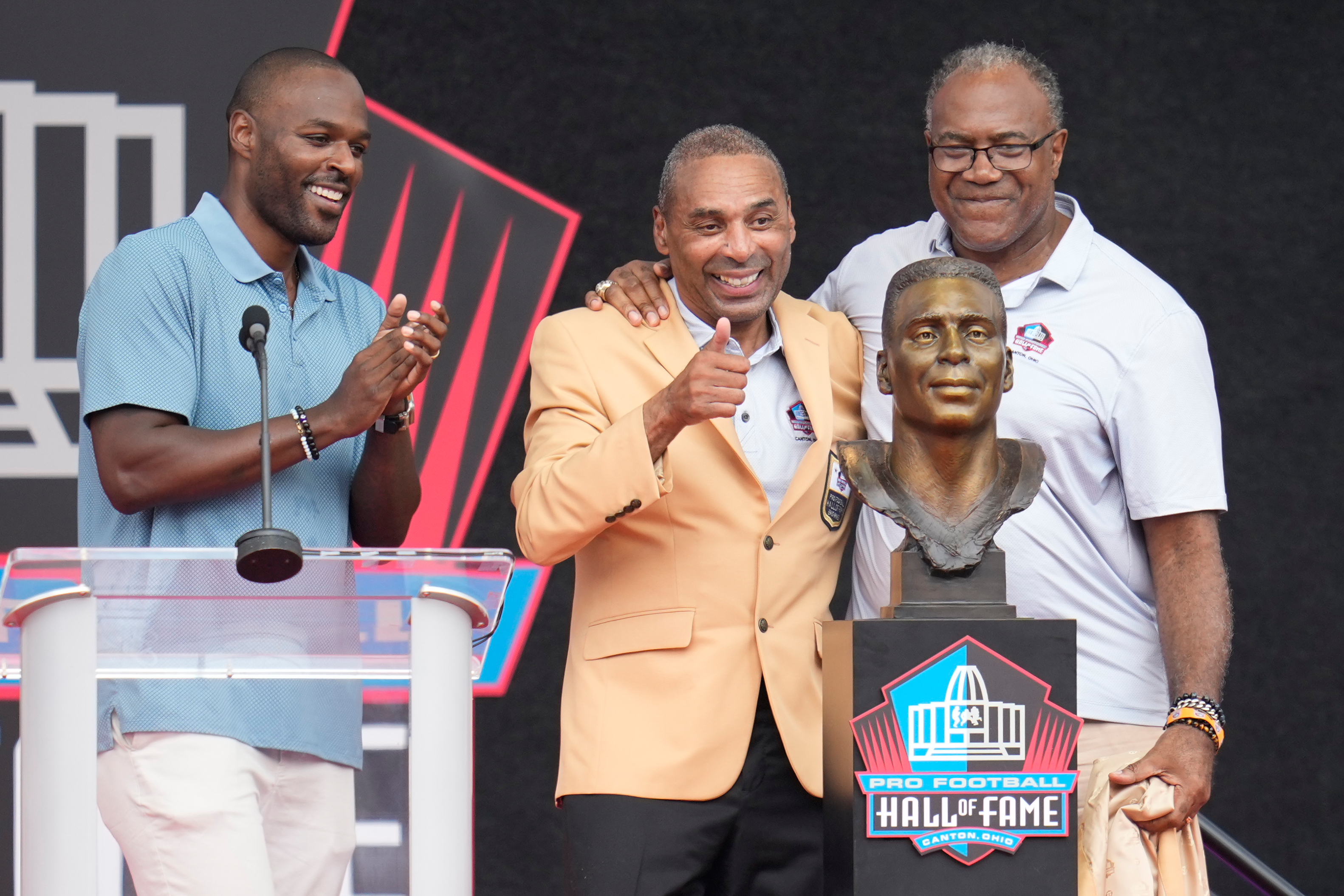 Former NFL player Roger Craig, center, unveils his bust with son, Roderick Craig, left, and Jamie Williams during the Pro Football Hall of Fame induction ceremony at the Pro Football Hall of Fame, in Canton, Ohio, Saturday, Aug. 8, 2026. 