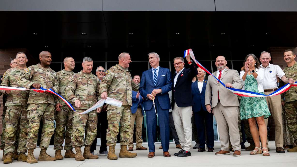 From center left, Lt. Gen. Robert D. Harter, retired Maj. Gen. Peter S. Cooke, and University of Utah President Taylor Randall cheer while joined by other officials as they take part in a ribbon-cutting ceremony for the Camp Williams "Deadeye" Army Reserve Center in Bluffdale on Saturday.