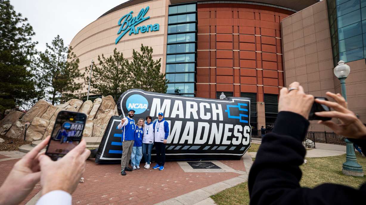 BYU fans Josh and Jamie Ogle, of Draper, and Mary Jane and Jeff Ogle, of Castle Rock, Colo., pose in front of March Madness branding before at Ball Arena in Denver, Colo., on March 20, 2025.