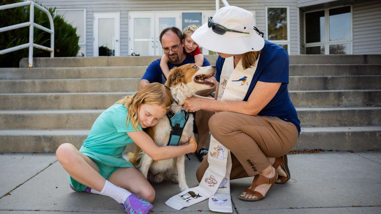 Pastor Sarah Merchant, front right, blesses her family’s dog Coda as her daughter Lydia Merchant, 10, front left, hugs Coda and husband Mac Merchant, back left, and son Spencer Merchant, 7, back right, watch during a Blessing of the Animals in conjunction with the celebration of the Hilltop United Methodist Church’s 125th anniversary at Hilltop United Methodist Church in Sandy on Saturday.