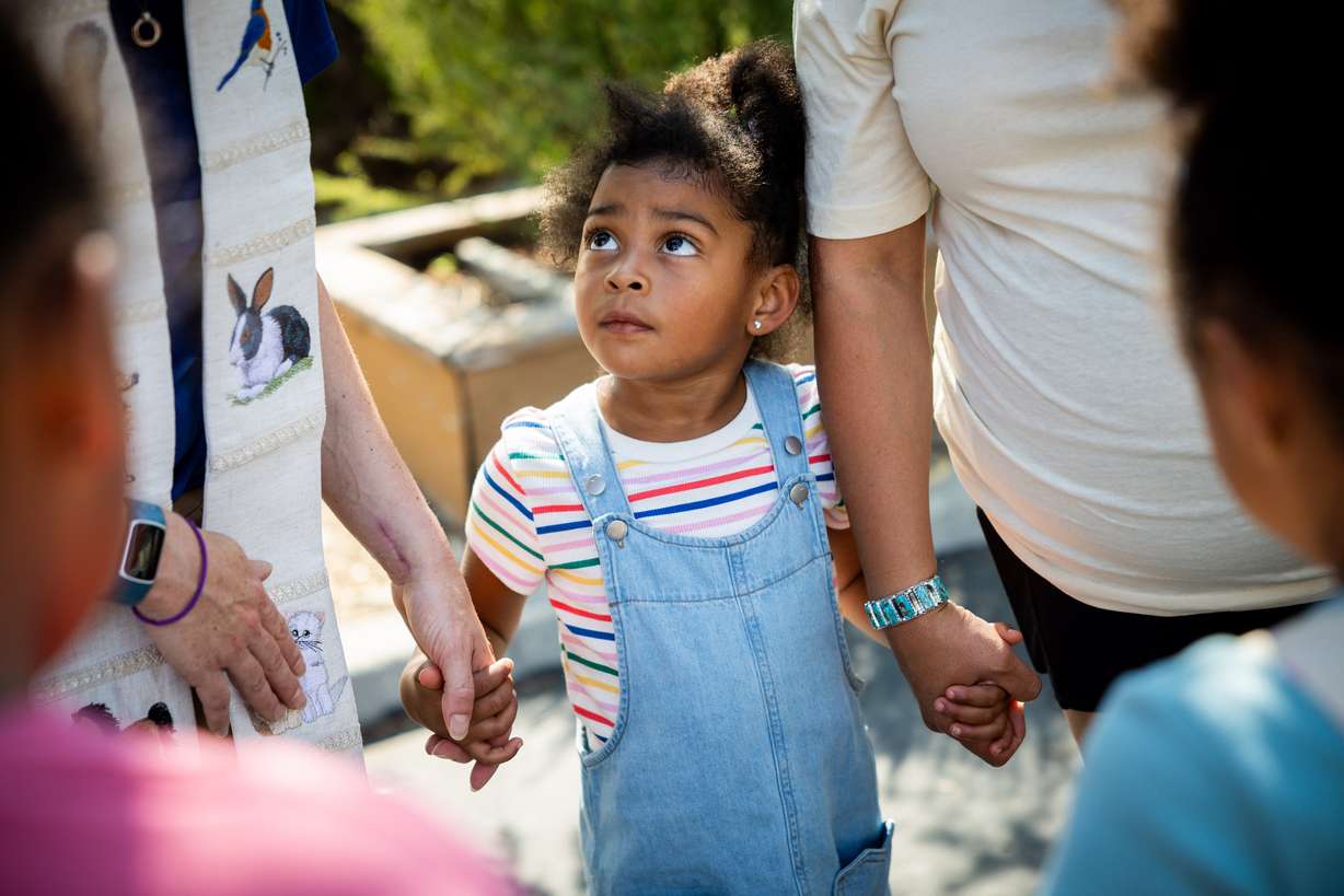Amina Adan, 4, center, looks up at Pastor Sarah Merchant as she blesses Adan’s family after their cat went missing during a Blessing of the Animals in conjunction with the celebration of the Hilltop United Methodist Church’s 125th anniversary at Hilltop United Methodist Church in Sandy on Saturday.