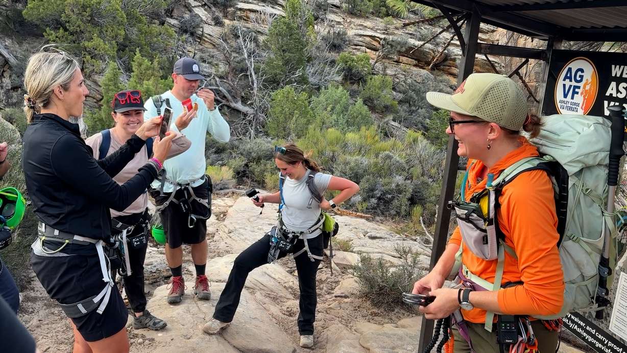 Amber Toler (right) instructs a group on the proper use of safety gear before starting on the via ferrata course.