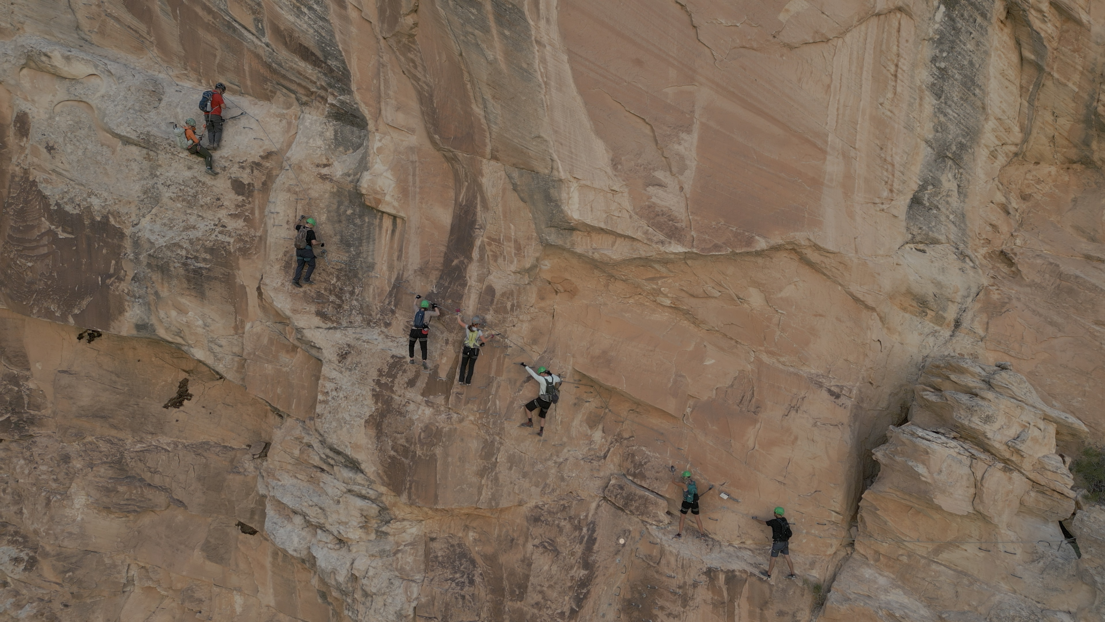 A group scales the via ferrata course along the side of a cliff, in Ashley Gorge.
