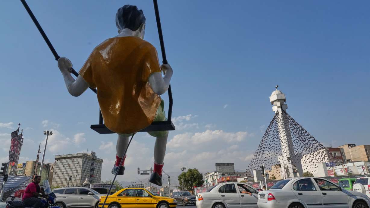 Vehicles drive past a statue of a swinging boy at a square in Tehran, Iran, Monday. Yemeni authorities on Tuesday said at least six were killed in a Houthi attack on a vessel.