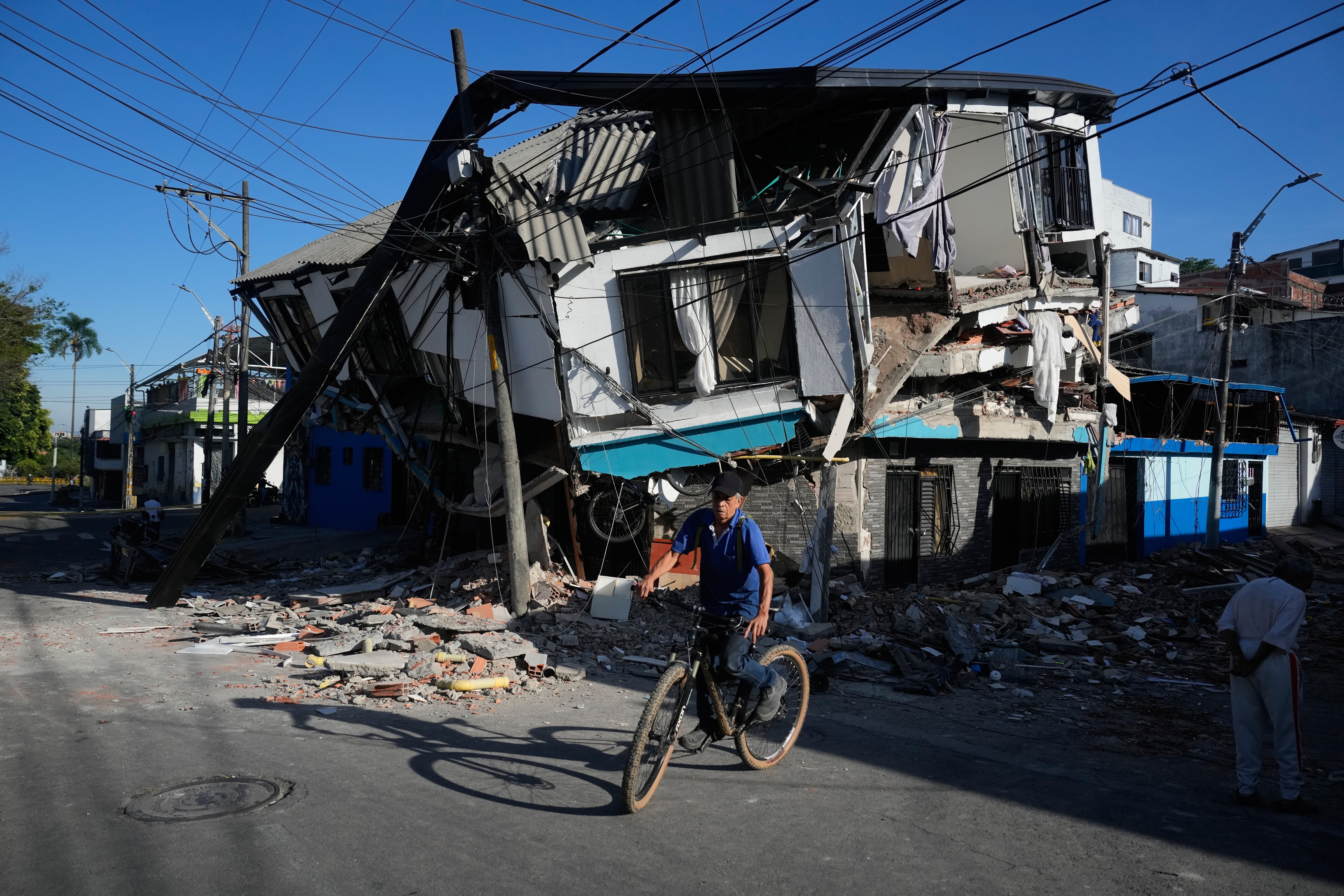 A neighbor rides past damaged homes a day after an earthquake struck Pereira, Colombia, on Tuesday. At least 181 people have been killed.