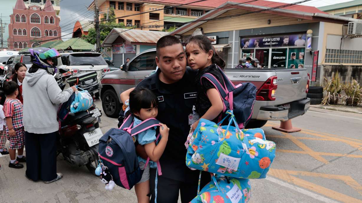 A man carries schoolgirls outside the site of a school shooting in Thailand's Nonthaburi province, Friday. The government pledged Wednesday to tighten gun controls after two shootings in less than a week.