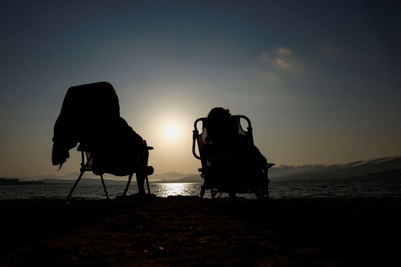 Patricia Molera and Enrique Sotomayor test their eclipse glasses during sunset at Arija beach, Spain, Tuesday. Glasses like these are going fast for Wednesday's eclipse.