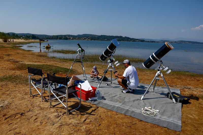 Frenchman Leyssalle Anthony, 39, prepares a telescope to view the total solar eclipse from the beach, in Arija, Spain, Wednesday. Heat and wildfires are the concerns among officials for those wanting to view the eclipse.