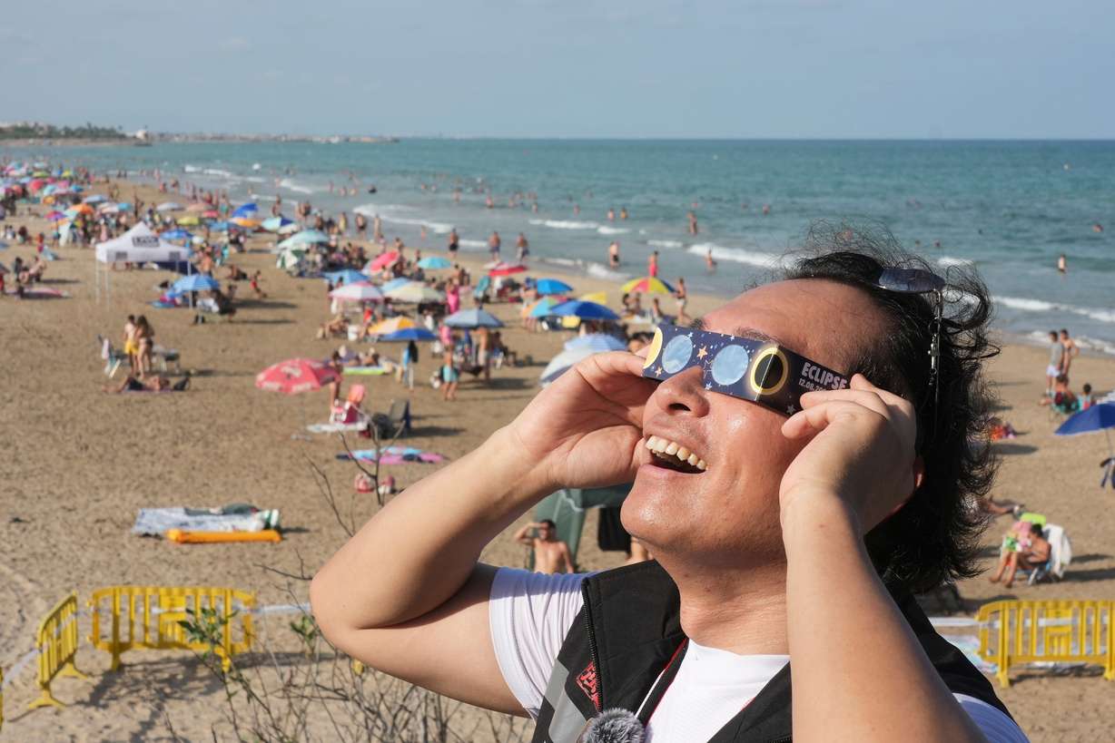 A man wears special eclipse glasses, as beachgoers gather before a total solar eclipse set to begin around sunset, at a beach near Valencia, Spain, Wednesday. Eclipse glasses like these went fast.