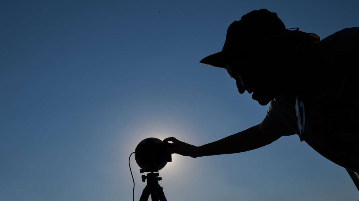 A member of the "Los Taraos" amateur astrophotography group, sets up his camera to shoot a total solar eclipse in Berlanga de Duero, central Spain, Wednesday. Millions crowded amid heat and wildfire concerns to catch a glimpse of the eclipse.