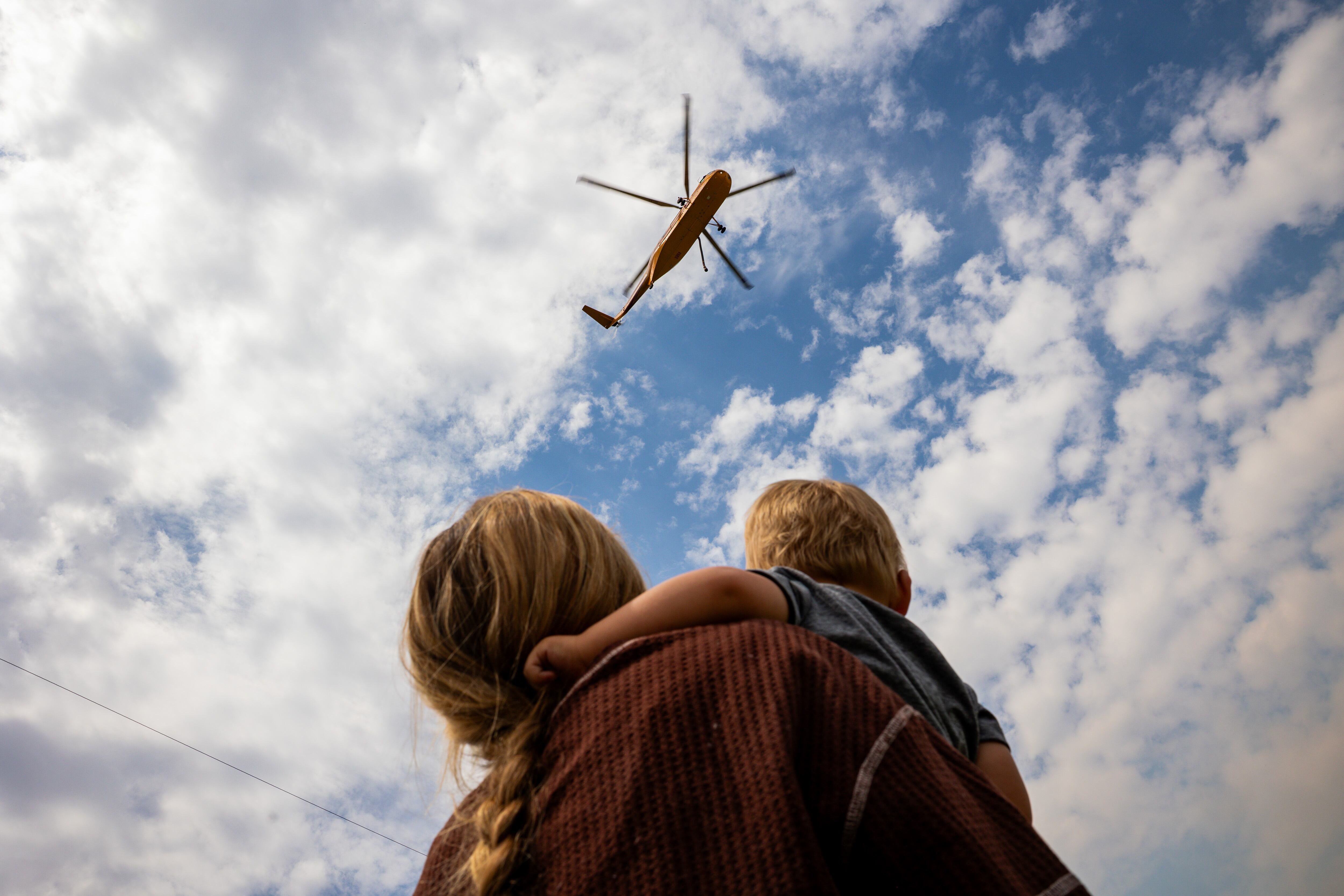 Sisalee Richins Beddoes and son Gus watch a firefighting helicopter travel to refill its bucket in a pool full of water in Henefer to fight the Rocky Canyon Fire on Tuesday. This year's fire season has already cost Utah millions in resources.