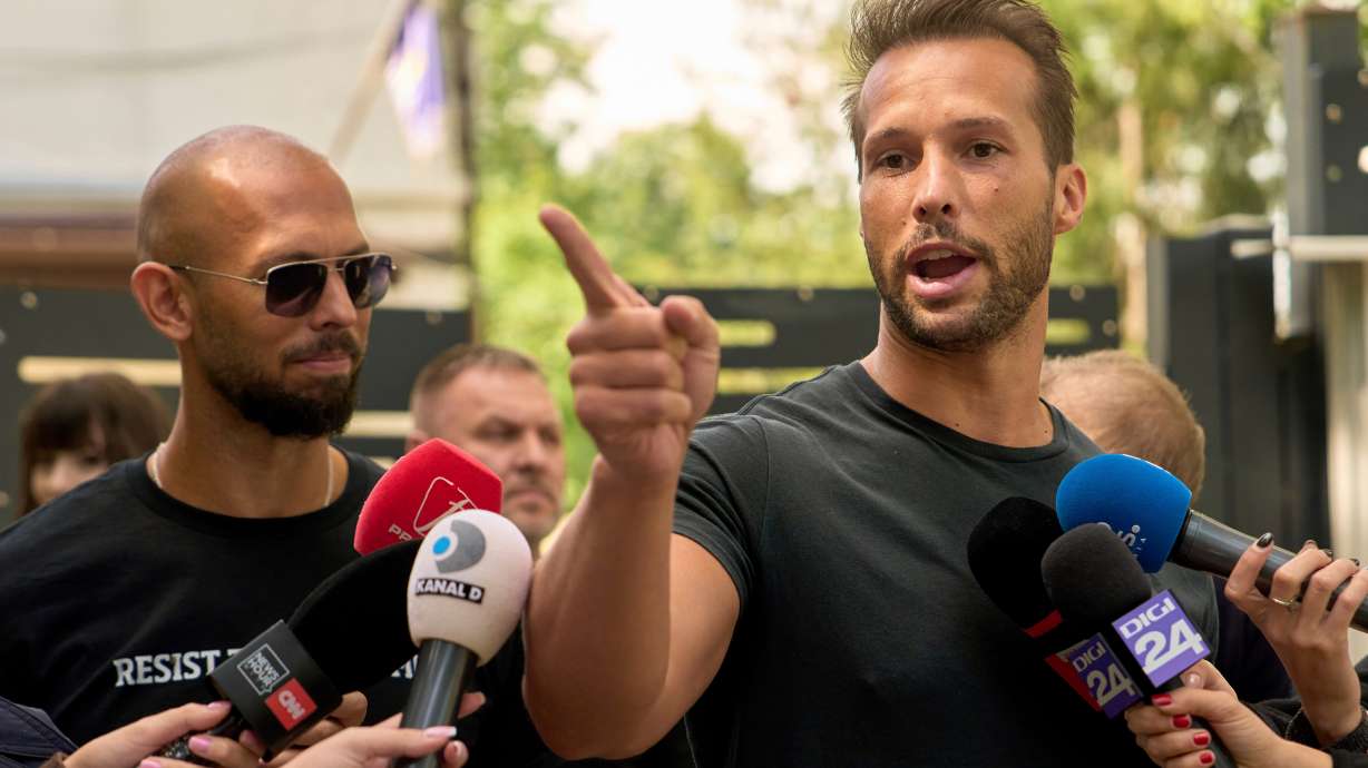 Andrew Tate watches his brother Tristan speak outside a police station in Voluntari, Romania, May 21, 2025. A judge postponed a hearing on the brothers staying in custody on Thursday.