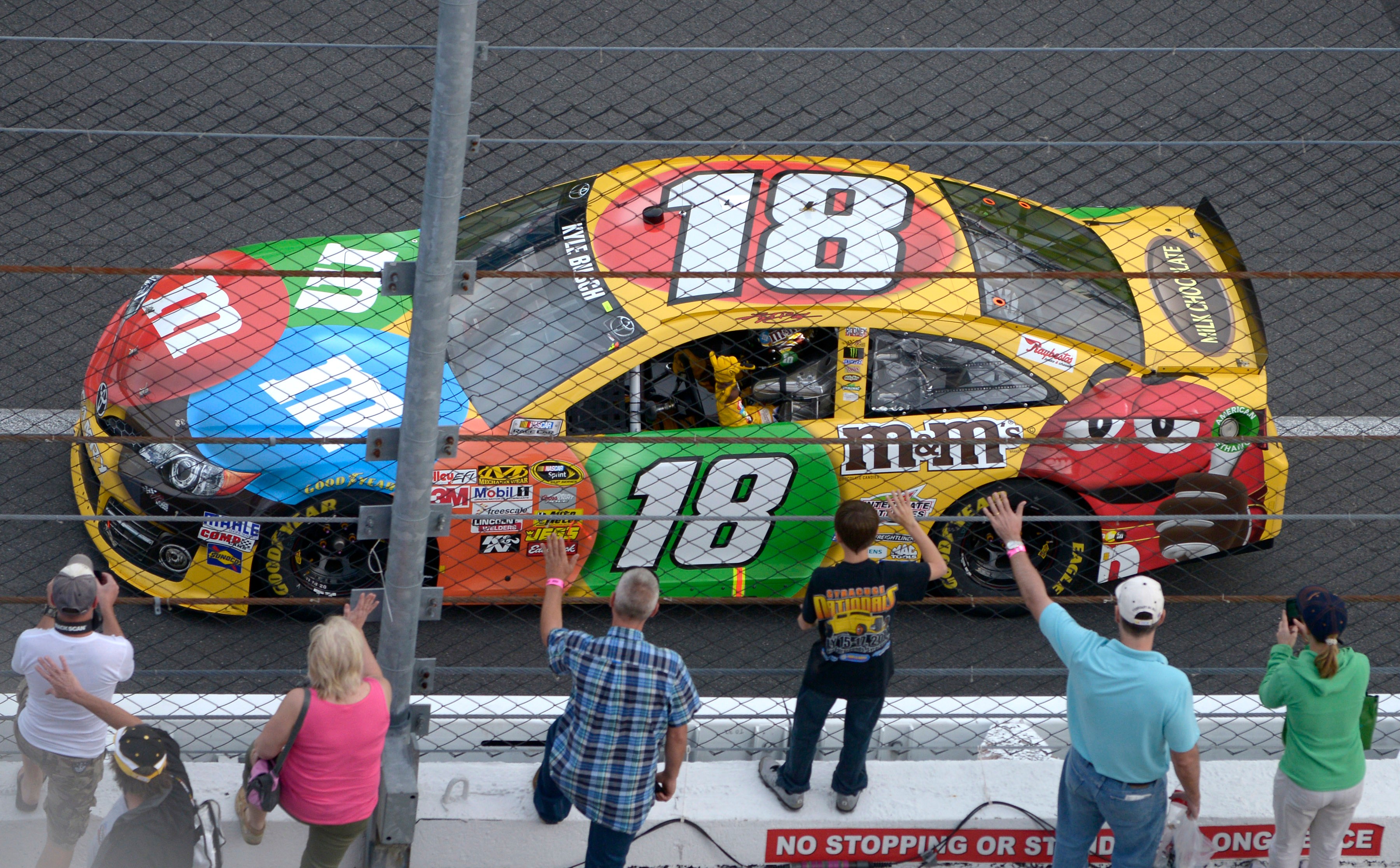 FILE - Kyle Busch waves to fans while doing a victory lap after winning the second of two 150-mile qualifying races for Sunday's NASCAR Daytona 500 auto race at Daytona International Speedway in Daytona Beach, Fla., Feb. 21, 2013. 