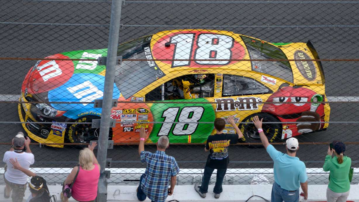 FILE - Kyle Busch waves to fans while doing a victory lap after winning the second of two 150-mile qualifying races for Sunday's NASCAR Daytona 500 auto race at Daytona International Speedway in Daytona Beach, Fla., Feb. 21, 2013.