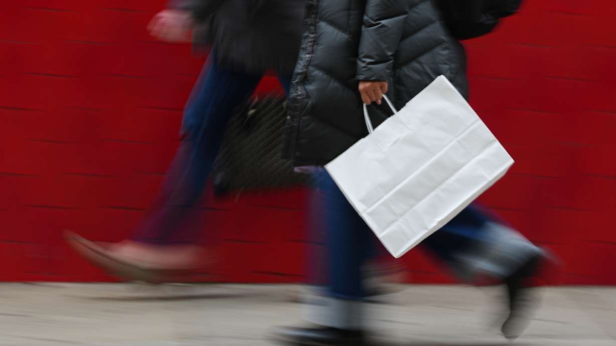 A person carries a shopping bag in Philadelphia, Dec. 10, 2025. After splurging on the World Cup and Amazon Prime Day sales, Americans unexpectedly cut their spending in July by the biggest amount in more than a year.