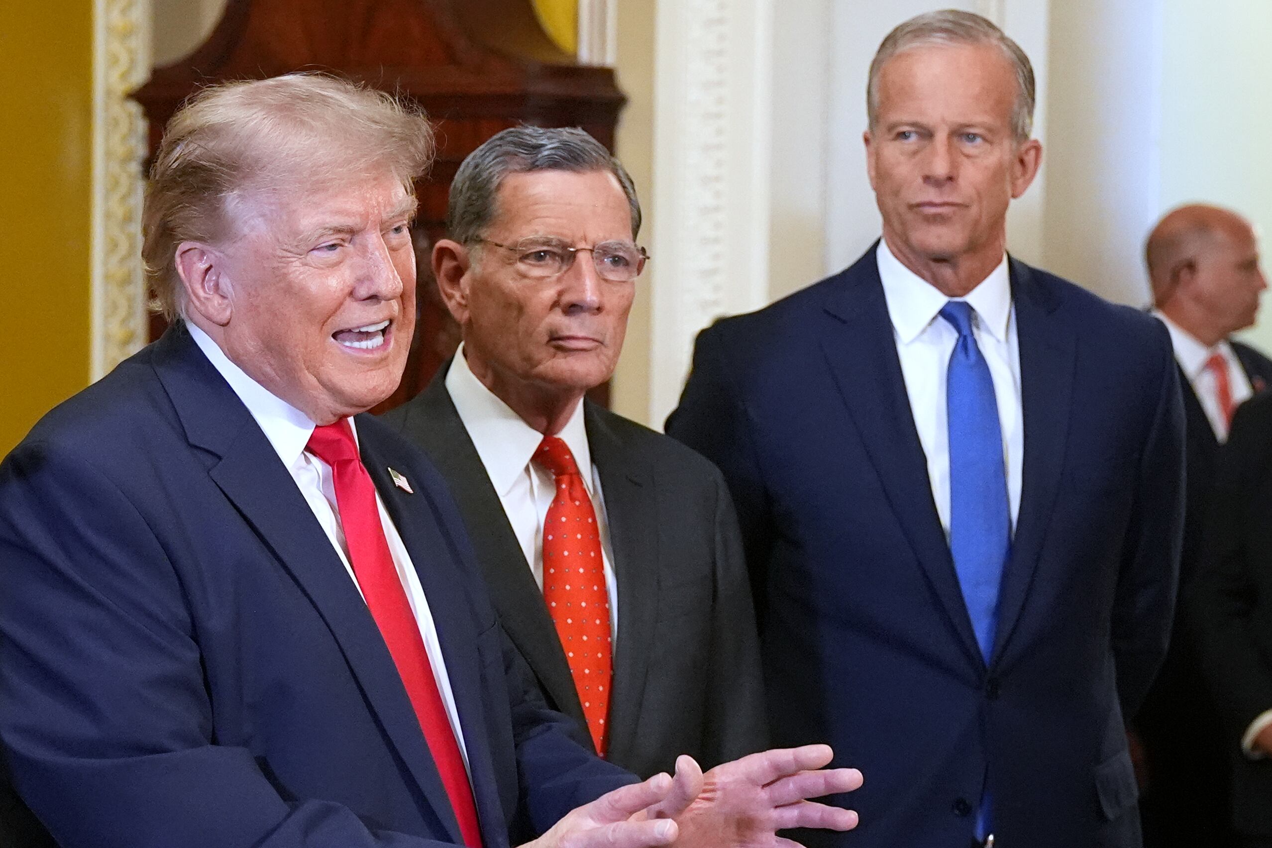 President Donald Trump speaks with reporters as Sen. John Barrasso, R-Wyo., and Senate Majority Leader John Thune, R-S.D., listen on Capitol Hill, June 24, in Washington.