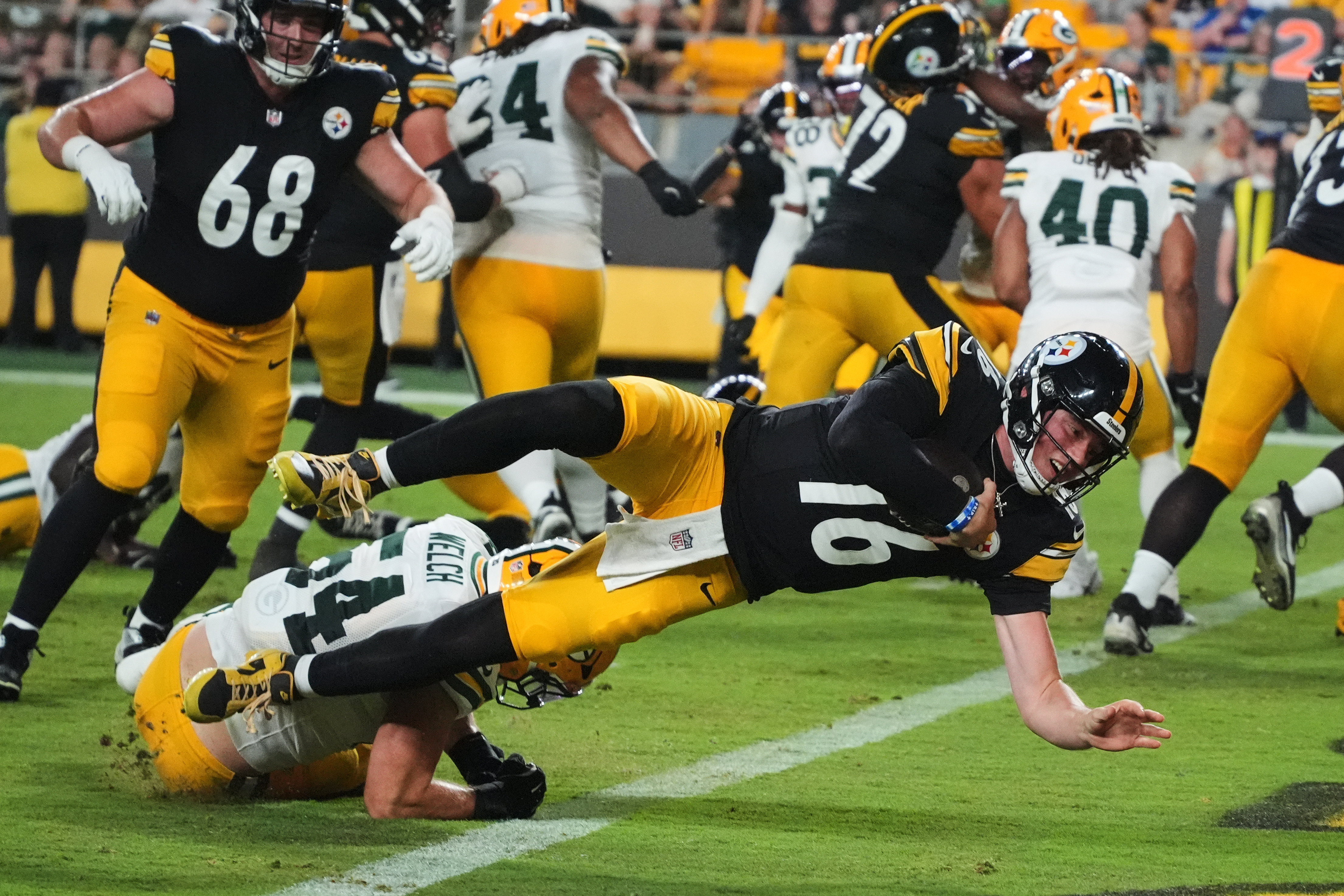 Pittsburgh Steelers quarterback Drew Allar (16) divers over Green Bay Packers linebacker Kristian Welch into the end zone for a touchdown in the second half of a preseason NFL football game in Pittsburgh, Thursday, Aug. 13, 2026. 