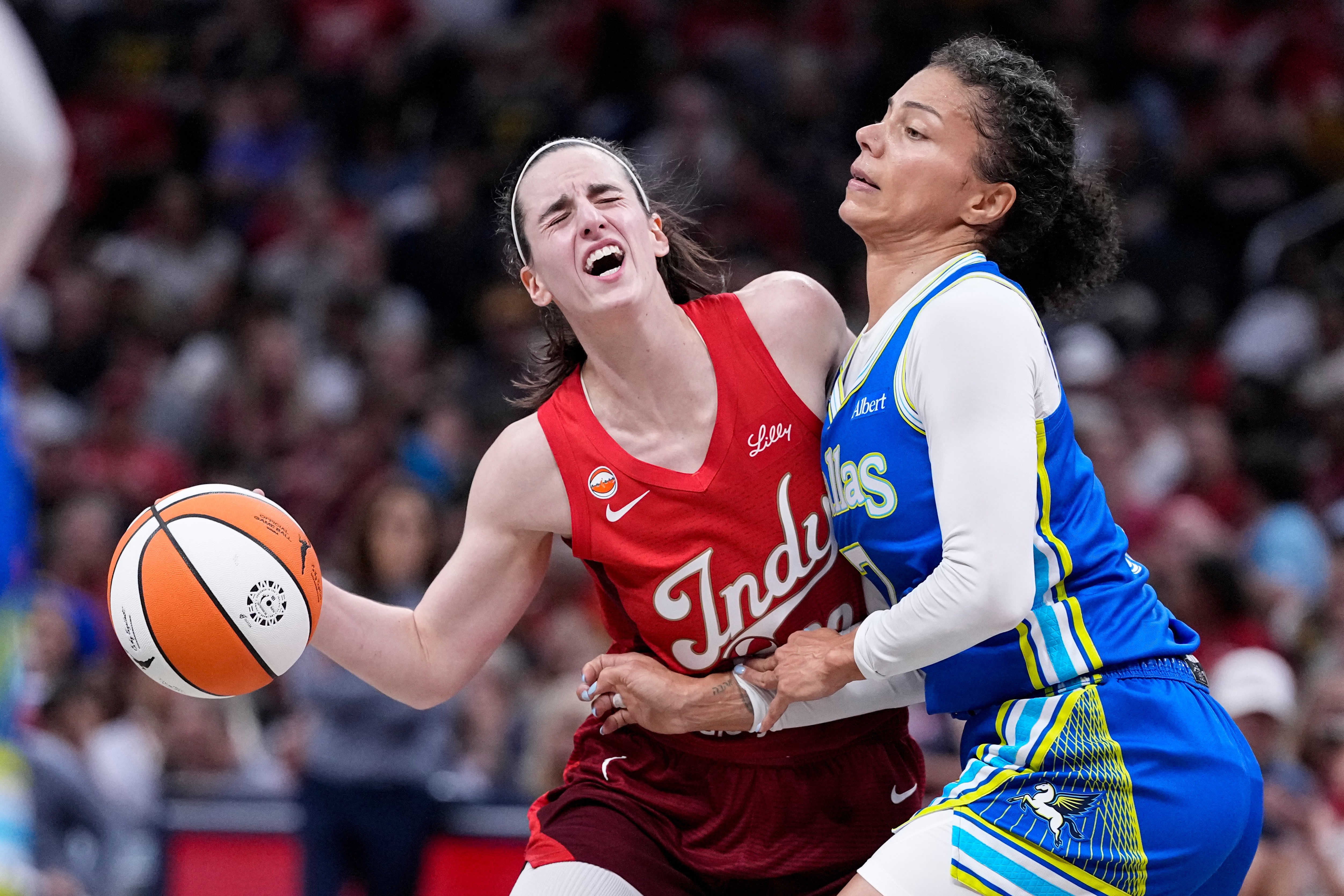 Indiana Fever guard Caitlin Clark, left, is fouled by Dallas Wings forward Alysha Clark, right, in the first half of a WNBA basketball game in Indianapolis, Friday, Aug. 14, 2026. 