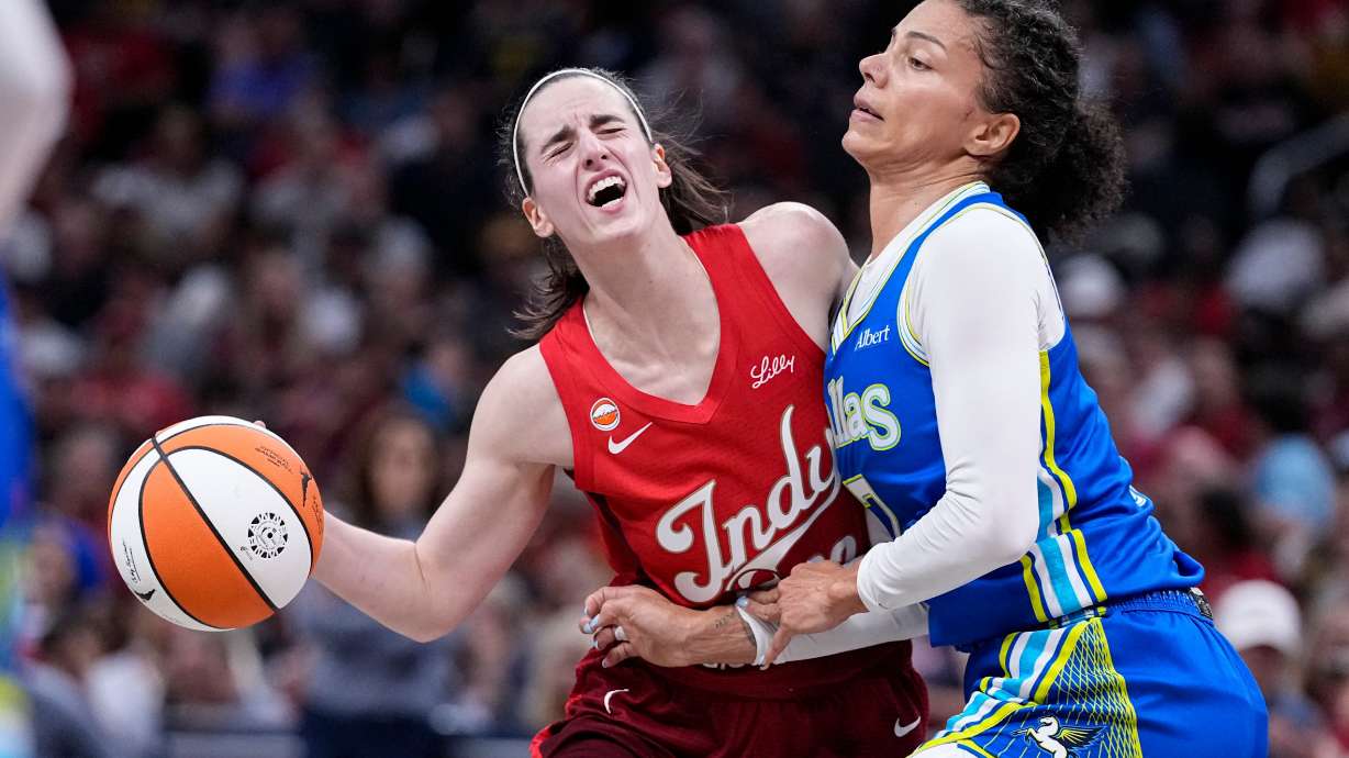Indiana Fever guard Caitlin Clark, left, is fouled by Dallas Wings forward Alysha Clark, right, in the first half of a WNBA basketball game in Indianapolis, Friday, Aug. 14, 2026.